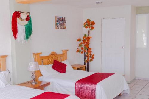 a bedroom with two beds with red and green blankets at Hotel Carnaval in Huejotzingo