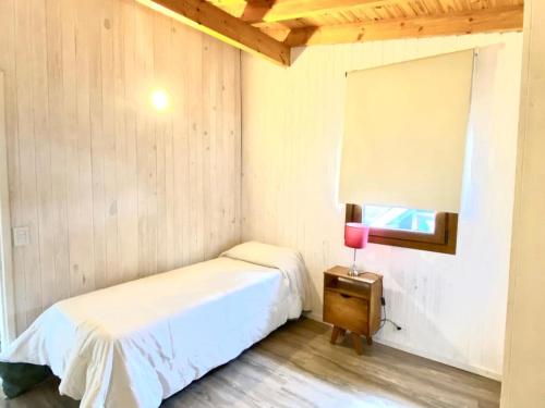 une chambre avec un lit et une table avec une lampe dans l'établissement Departamentos Tres Maitenes, à Villa La Angostura