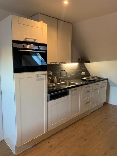 a kitchen with white cabinets and a sink and a stove at De oude hooizolder in Ulrum