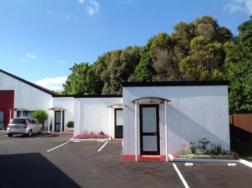 a white building with a car parked in a parking lot at Cascades Motor Lodge in Auckland