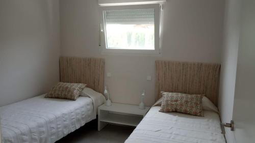 1 Schlafzimmer mit 2 Betten und einem Fenster in der Unterkunft Casita moderna a escasos metros de Playa Terranova in Oliva