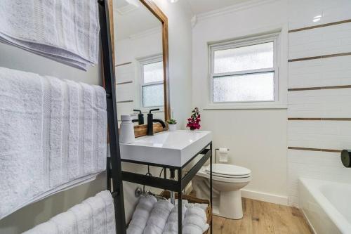 a bathroom with a sink and a toilet and a mirror at Central Lafayette location w/King Bed & Coffee Bar in Lafayette