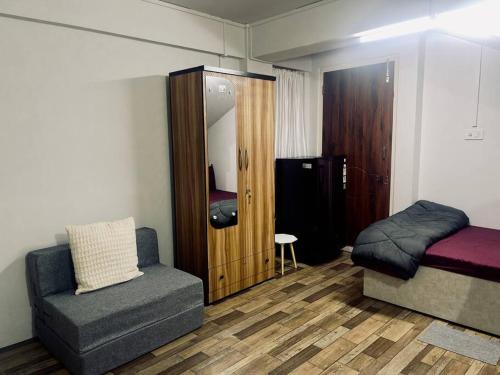 Zimmer mit einem Bett, einem Sofa und einem Stuhl in der Unterkunft JoeLene's Studio Apartment in Lapalang, Shillong in Shillong