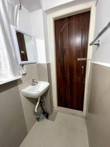 ein Badezimmer mit einem Waschbecken und einer Holztür in der Unterkunft JoeLene's Studio Apartment in Lapalang, Shillong in Shillong