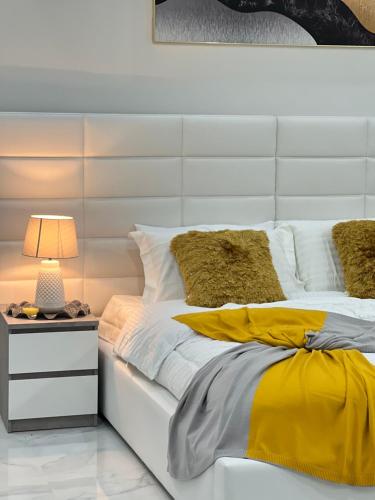 una cama blanca con sábanas amarillas y blancas y una lámpara en Sky ittin سما إتين en Salalah