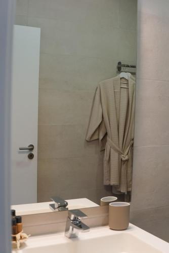 a bathroom mirror with a robe hanging above a sink at A Casa de Cima - Cacela Velha in Vila Nova De Cacela