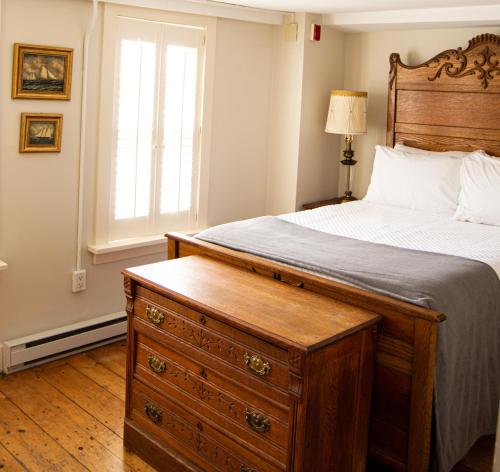 a bedroom with a bed with a dresser and a window at The General Stanton Inn in Charlestown