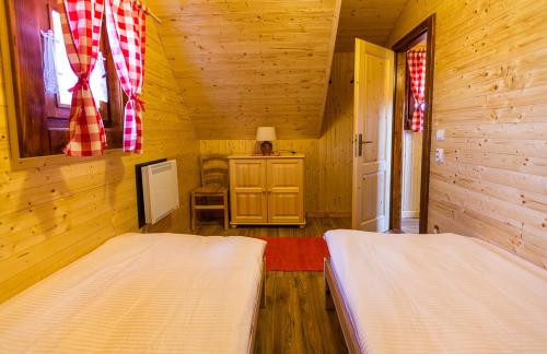 a bedroom with two beds in a wooden cabin at Ubytovanie Koliba Pacho - Zrub Katka in Prievidza
