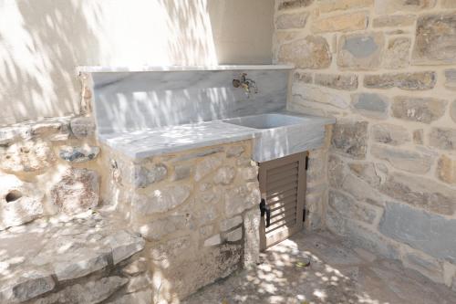 Baño de piedra con lavabo y pared de piedra en Faistos Cottage, en Áyios Ioánnis