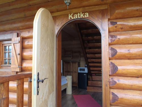 an open door to a log cabin with a surfboard at Ubytovanie Koliba Pacho - Zrub Katka in Prievidza
