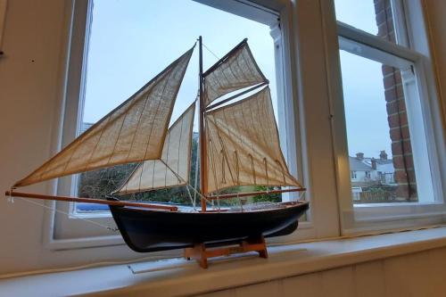 a model of a boat sitting in a window at 3 The Old Schoolhouse: hot tub, log burner, parking, en-suite in Whitstable
