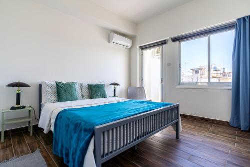 a bedroom with a bed with blue sheets and a window at Engomi Apartment in Yukarı Lakatamya