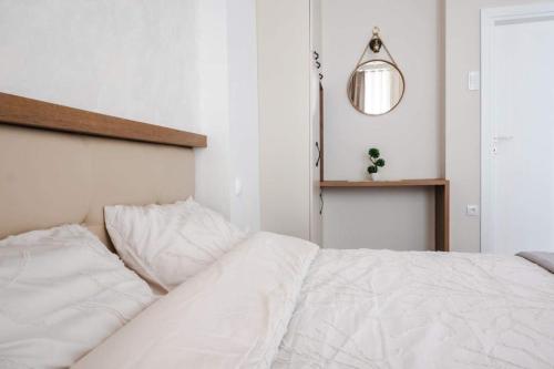 a white bed in a white bedroom with a mirror at MariaApartments in Bitola