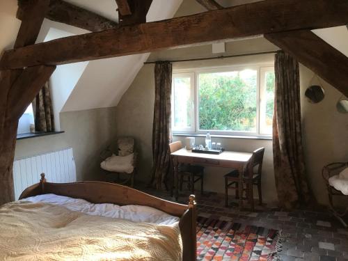 a bedroom with a bed and a desk and a window at La ferme aux oiseaux B&B in Beaumont