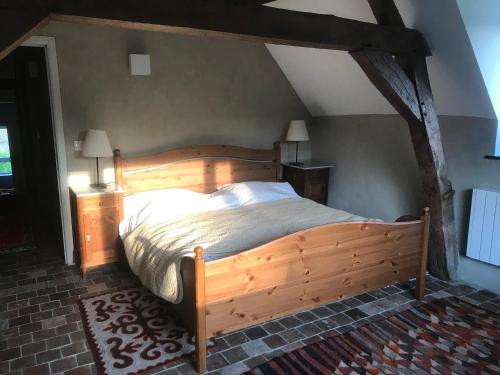 una camera da letto con letto in legno in mansarda di La ferme aux oiseaux B&B a Beaumont