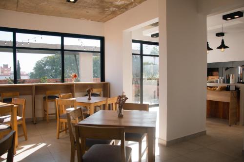een eetkamer met tafels, stoelen en ramen bij Usina Studio FMA-Coliving in Salta