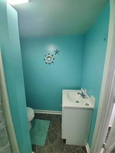 Baño azul con aseo y lavamanos en Dagsboro Retreat Beautiful 2 Bed and 1 Bath Villa, en Dagsboro