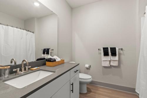 Luxury Condo in Ybor City Tampa w/Pool access في تامبا: حمام أبيض مع حوض ومرحاض