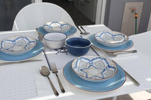 a table with blue and white plates and utensils on it at Sunset Thalassa View Flat in Ofrínion