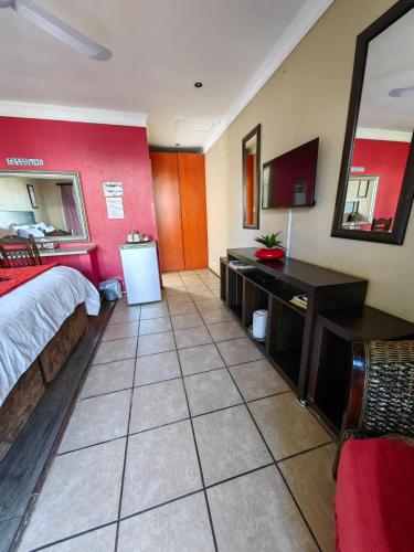 um grande quarto de hotel com uma cama e uma secretária em Leondale Guest House em Germiston