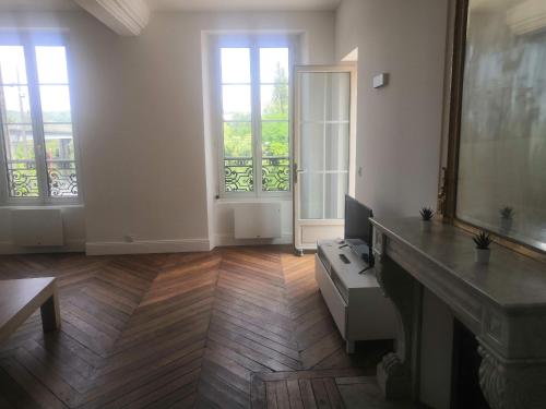 a living room with a fireplace and two windows at Grand 2P Terrasse bord de seine in Mantes-la-Jolie