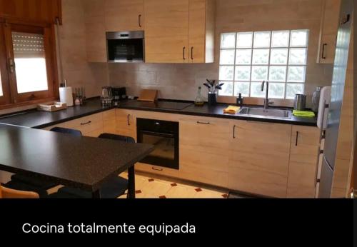 a kitchen with wooden cabinets and a table in it at Increíble Casa Rural en la Sierra de Altomira Piscina privada y Barbacoa in Albalate de Zorita