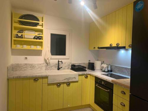 a kitchen with yellow cabinets and a sink at Syboro in Aloïziánika