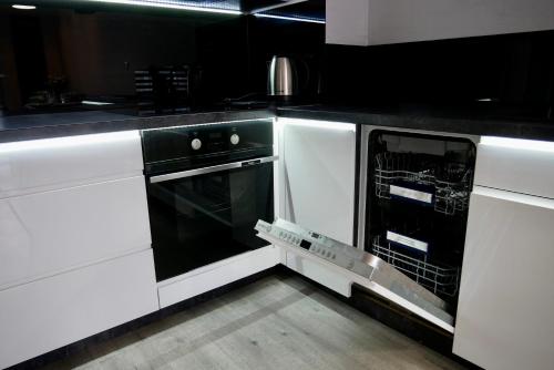 uma cozinha com armários brancos e uma máquina de lavar louça aberta em APARTAMENT PAKO z miejscem w garażu podziemnym em Toruń