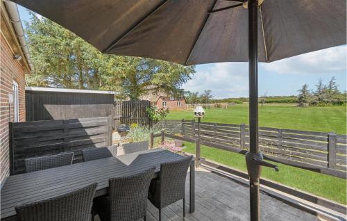 a wooden table with an umbrella on a patio at Gorgeous Home In Rømø With Wifi in Bolilmark