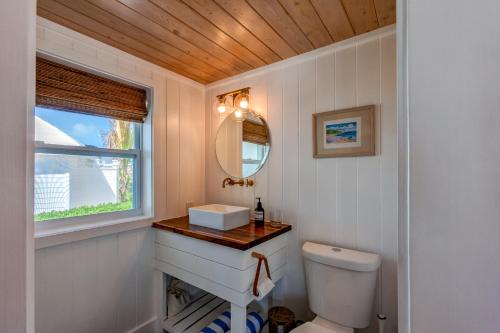 Un baño con un inodoro blanco y un espejo. en Elbow Reef, en Hope Town
