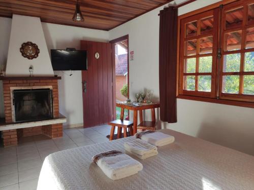 a bedroom with a bed and a fireplace at Pousada Encantus in Monte Verde