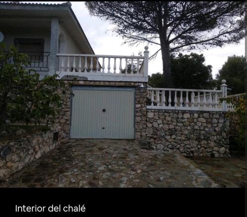 a building with a white gate and a stone wall at Increíble Casa Rural en la Sierra de Altomira Piscina privada y Barbacoa in Albalate de Zorita