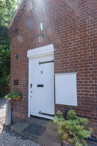 a brick building with a white door and a brick wall at 3 The Old Schoolhouse: hot tub, log burner, parking, en-suite in Whitstable