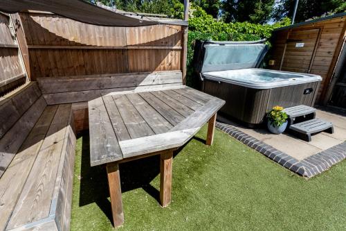 a wooden bench sitting next to a hot tub at 3 The Old Schoolhouse: hot tub, log burner, parking, en-suite in Whitstable
