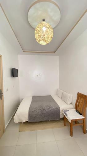 een slaapkamer met een bed en een kroonluchter bij Dar nor in Essaouira