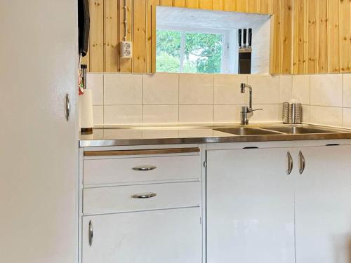 a kitchen with white cabinets and a sink at Holiday home Huaröd in Huaröd