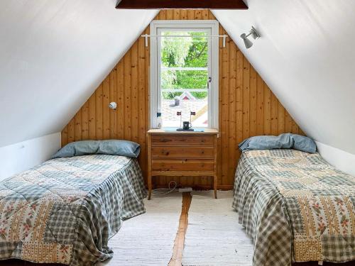 a attic bedroom with two beds and a window at Holiday home Huaröd in Huaröd