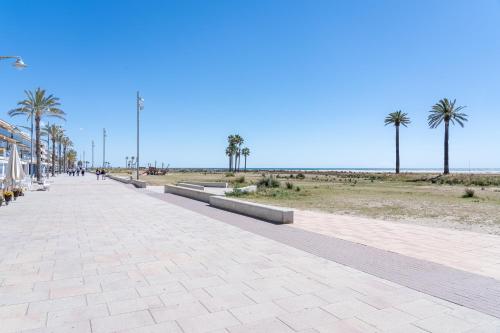 a sidewalk next to a beach with palm trees at 1ª LÍNEA DE PLAYA. Apartamento: LA CALMA in Comarruga