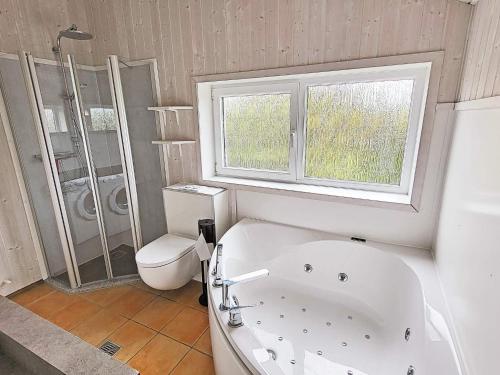 een badkamer met een bad, een toilet en een raam bij Three-Bedroom Holiday home in Grömitz 13 in Grömitz