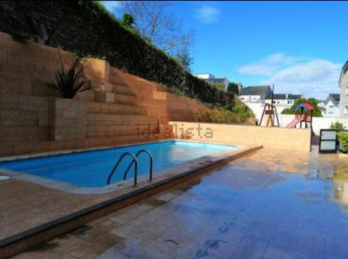 a swimming pool in front of a wall with asevere at Suite XIMENA con piscina in Viveiro