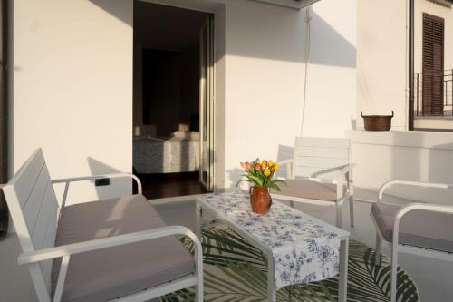 un porche con sillas blancas y una mesa con un jarrón de flores en suite la corte en Sannicandro di Bari