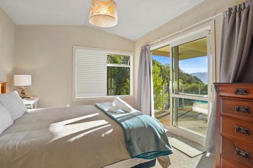 a bedroom with a bed and a large window at Kaioruru View - Diamond Harbour Holiday Home in Diamond Harbour