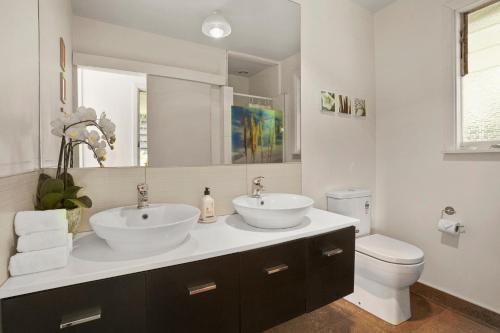a bathroom with two sinks and a toilet at Kaioruru View - Diamond Harbour Holiday Home in Diamond Harbour
