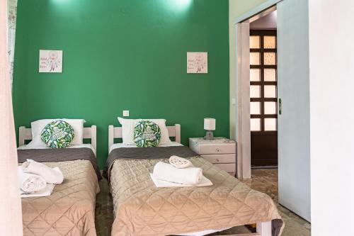 a bedroom with two beds and a green wall at Ritsinia Apartments in Aigio