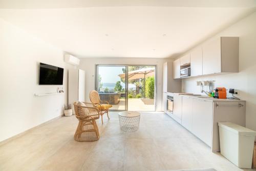 une cuisine avec des armoires blanches et une table et des chaises dans l'établissement CASA LC VILLA 2-3 pers vue mer jacuzzi, à Ajaccio