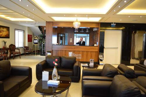 a lobby with leather couches and a man standing at a podium at Ream Hotel Amman in Amman
