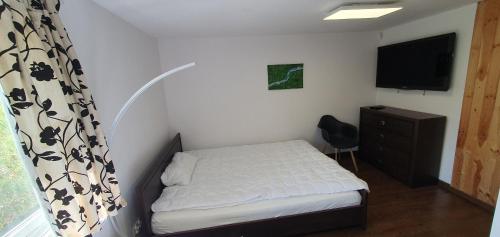 - une petite chambre avec un lit et une télévision dans l'établissement Pod modrzewiem, à Ostrzyce