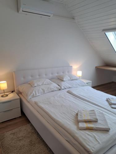 "ハルカーニャ"にあるEMMA Apartman Harkányの白いベッド(タオル2枚付)が備わります。