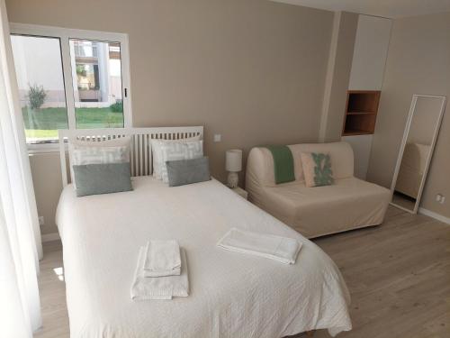 um quarto com uma cama branca e uma cadeira em Impervila 201 em Vilamoura