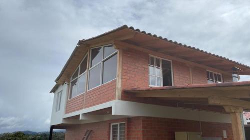 a red brick house with white windows on it at Finca Dulce María J&M Hospedaje Rural in Tunja